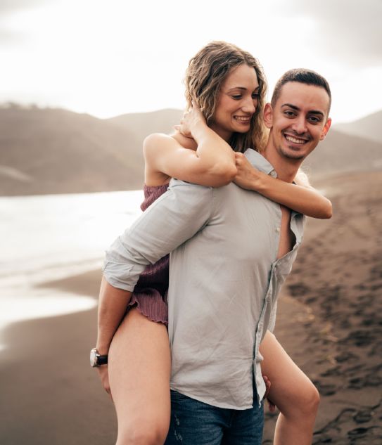 Pareja abrazada con la playa de fondo